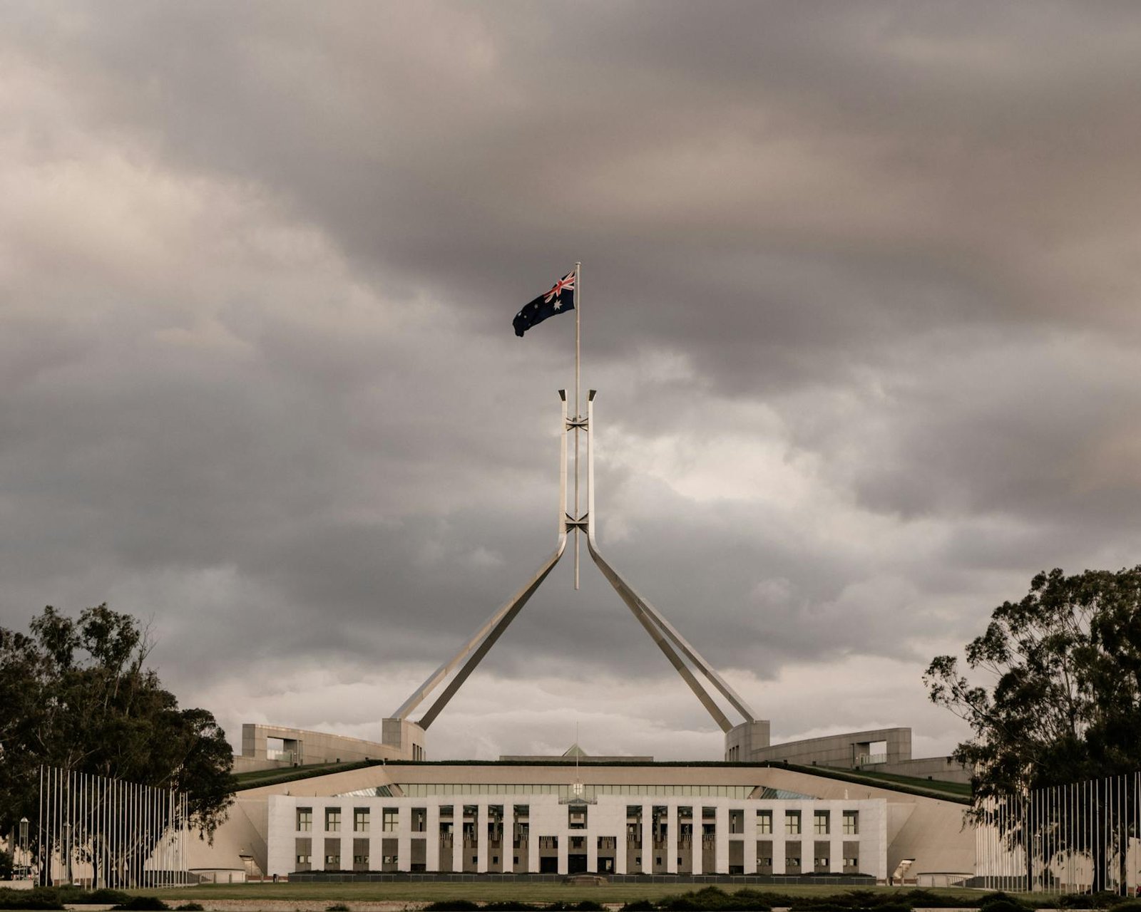 The Parliament House of Australia in Canberra with a dramatic cloudy backdrop.