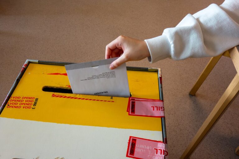 A voter drops a ballot envelope into a ballot box at a polling station